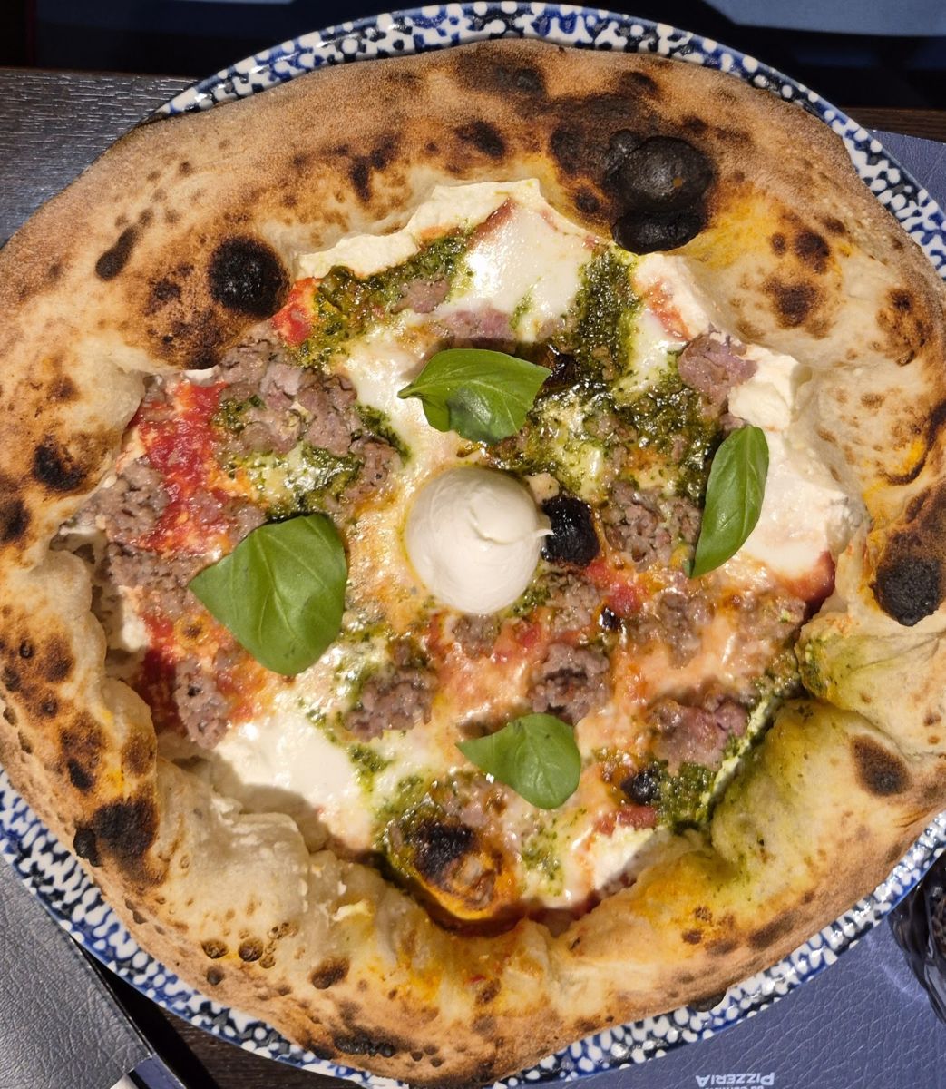 Una pizza servita su un piatto di maiolica siciliana bianca e blu